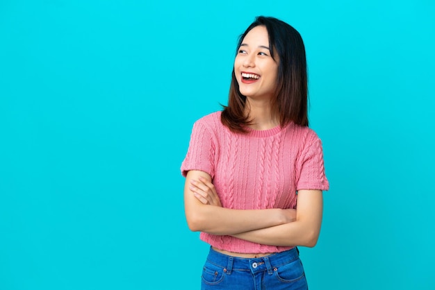 Jovem vietnamita isolada em um fundo azul feliz e sorridente