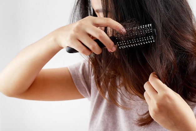 Jovem vista traseira preocupada com o problema da perda de cabelo, desequilíbrio hormonal, conceito de estresse. Muitos cabelos caem depois de penteados na escova de cabelo na mão. Mulher desembaraçou o cabelo com um pente, Cuidados de saúde