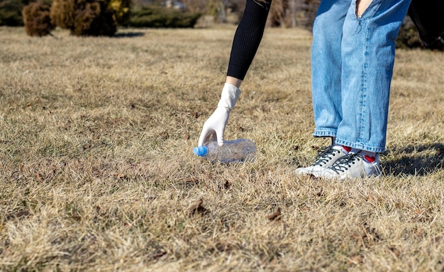 Foto jovem voluntária está pegando lixo da grama seca em uma coleta de lixo de parque público