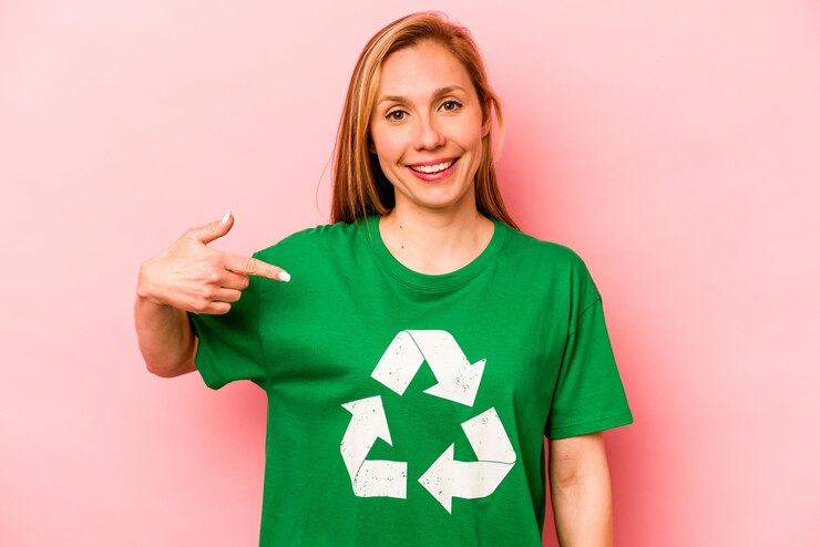 Foto jovem voluntária isolada na pessoa de fundo rosa apontando com a mão para um espaço de cópia de camisa orgulhoso e confiante