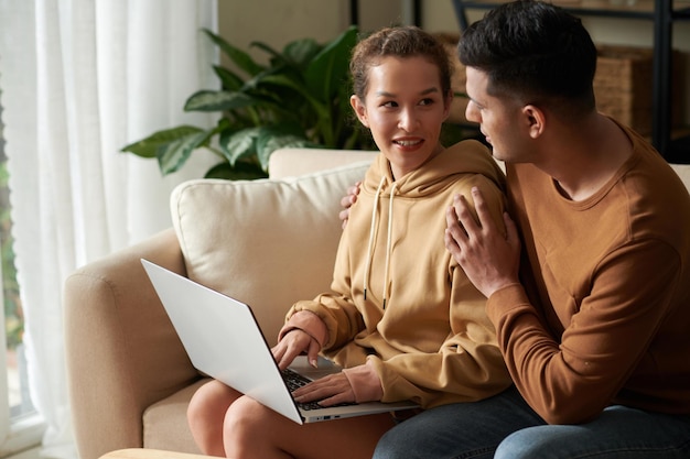 Joven abrazando a su novia cuando están discutiendo qué pedir para cenar