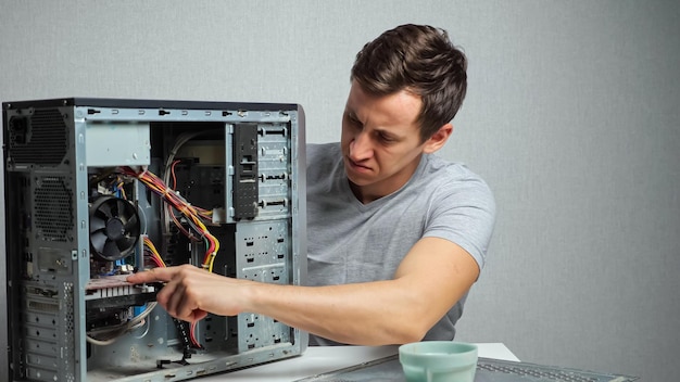 Foto joven abre una computadora muy polvorienta.