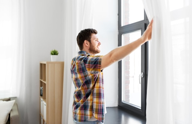 Foto joven abriendo la cortina de la ventana en casa