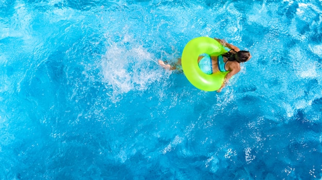 Joven activa está nadando en la piscina con anillo inflable