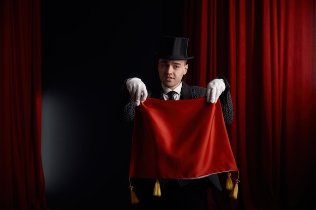 Foto joven actor mago que muestra un truco con una servilleta en una atmósfera misteriosa