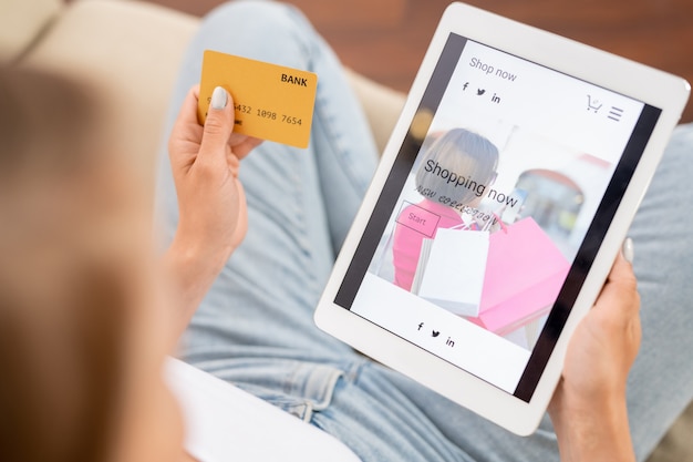 Joven adicto a las compras con tarjeta de crédito y tableta digital que va a mirar a través de la nueva colección de ropa casual en la tienda online