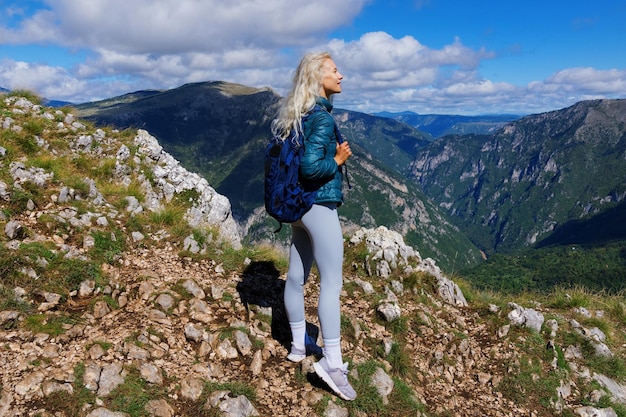 Una joven admira las vistas a la montaña después de hacer senderismo en verano