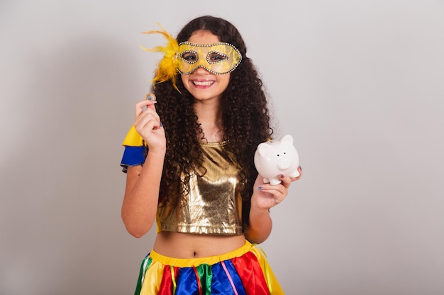 Joven adolescente brasileña con ropa de frevo carnaval con alcancía y moneda foto de primer plano