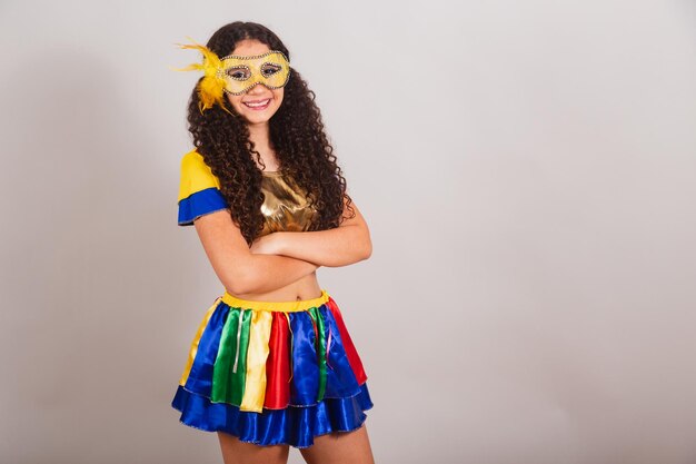 Joven adolescente brasileña con ropa de frevo máscara de carnaval con los brazos cruzados