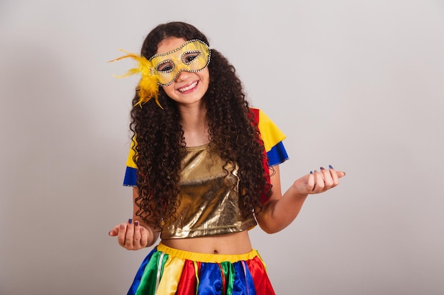 Joven adolescente brasileña con ropa de frevo máscara de carnaval invitando con las manos