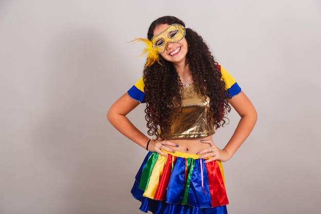 Joven adolescente brasileña con ropa de frevo máscara de carnaval con las manos en las caderas posando para la foto