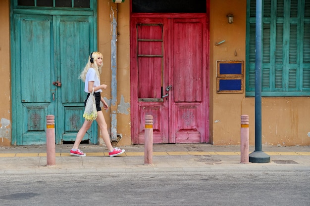 Joven adolescente caminando por la calle del fondo de puertas vintage de la ciudad vieja