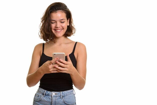 Joven adolescente caucásica feliz sonriendo y usando teléfono móvil