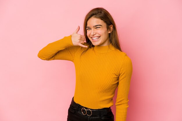 Joven adolescente caucásica flaca mostrando un gesto de llamada de teléfono móvil con los dedos.