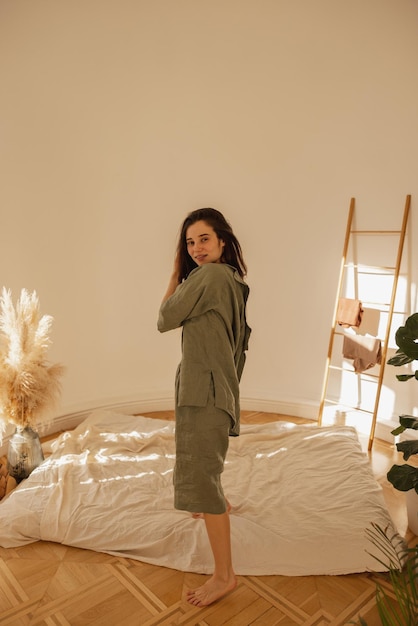 Joven adolescente caucásica posando mirando a la cámara mientras está de pie de lado en la habitación Morena viste ropa verde casual en temporada cálida Concepto de ocio de estilo de vida