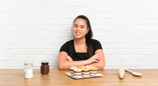 Joven adolescente chica asiática con un montón de pastel de muffins riendo