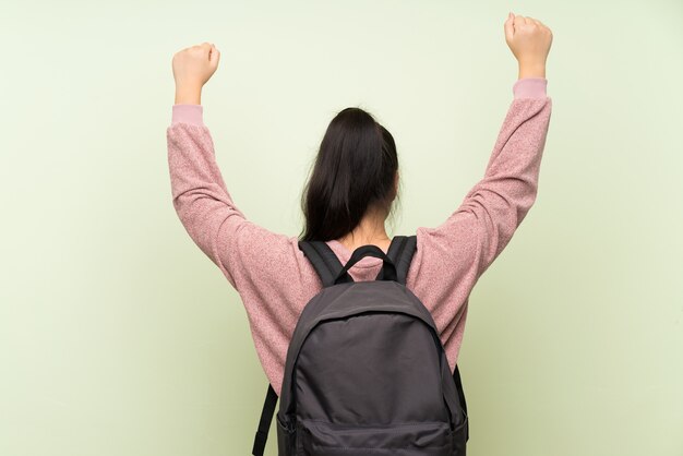 Foto joven adolescente chica asiática sobre fondo verde aislado con mochila