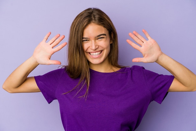 Joven adolescente chica flaca en la pared púrpura que muestra el número diez con las manos