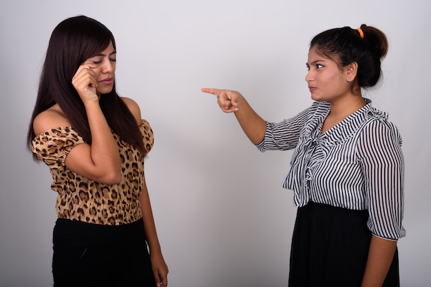 Joven adolescente enojado apuntando a una mujer joven llorando