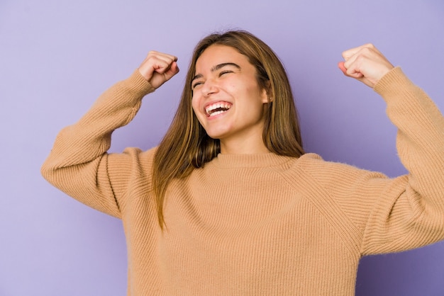 Joven adolescente flaca caucásica sobre fondo púrpura celebrando un día especial, salta y levanta los brazos con energía.