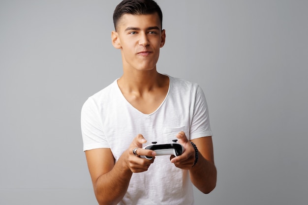 Joven adolescente jugando con la consola joystick sobre un fondo gris