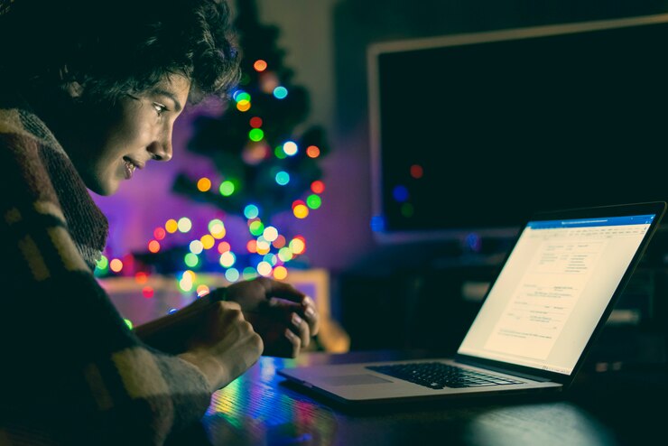 Foto joven adolescente masculino sentado en una manta en la mesa con el portátil en la noche y chatear con un amigo a través de la red social f