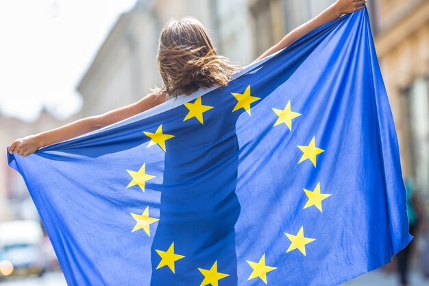 Joven adolescente ondeando con la bandera de la Unión Europea en la ciudad