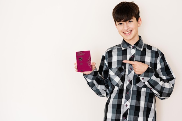 Joven adolescente con pasaporte de Chipre que se ve positivo y feliz de pie y sonriendo con una sonrisa segura contra el fondo blanco