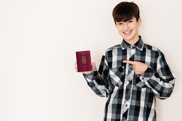 Joven adolescente con pasaporte danés que se ve positivo y feliz de pie y sonriendo con una sonrisa segura contra el fondo blanco