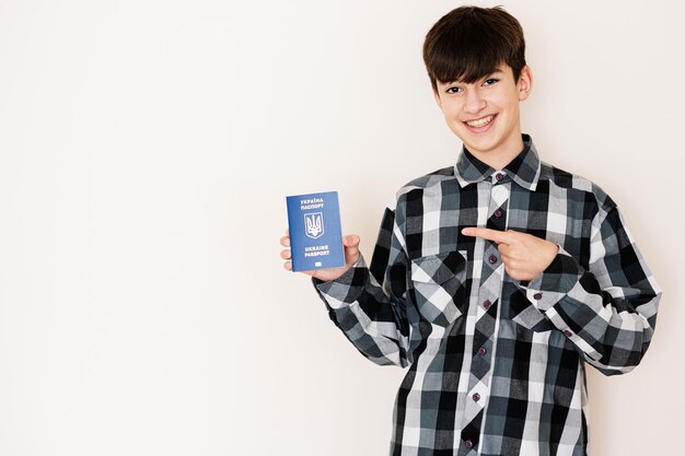 Foto joven adolescente con pasaporte ucraniano que se ve positivo y feliz de pie y sonriendo con una sonrisa segura contra el fondo blanco