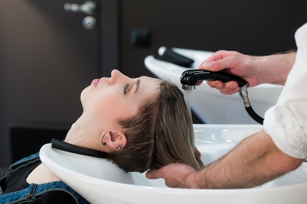 Joven adolescente en peluquería lavarse el cabello