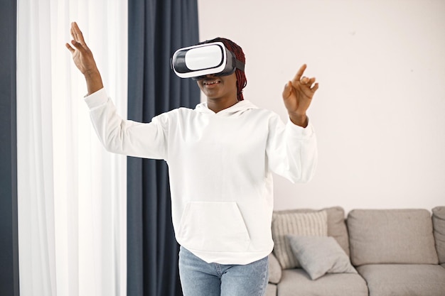 Joven adolescente de pie en la sala de estar con gafas de realidad virtual