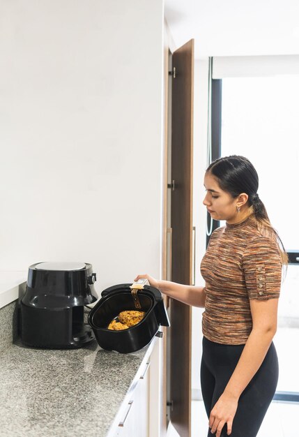 Foto joven adolescente sacando pollo frito con cereal de la freidora