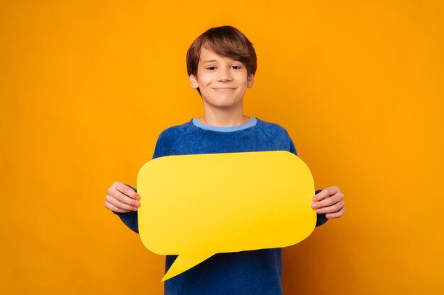 Un joven adolescente sonriente sostiene frente a su pecho un discurso de burbuja en blanco