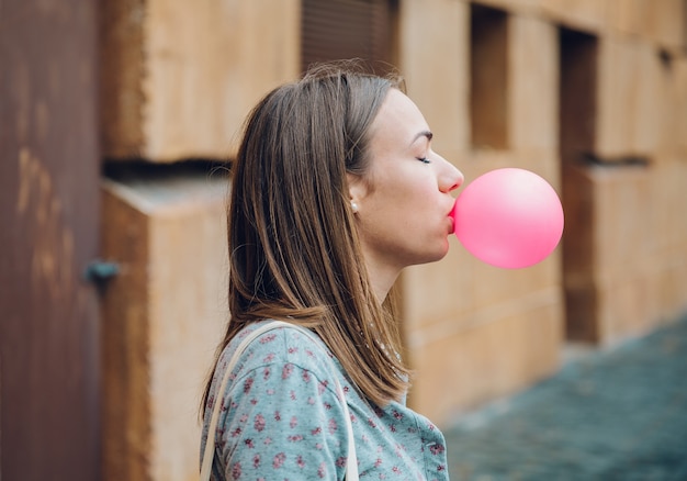 Joven adolescente soplando chicle rosa