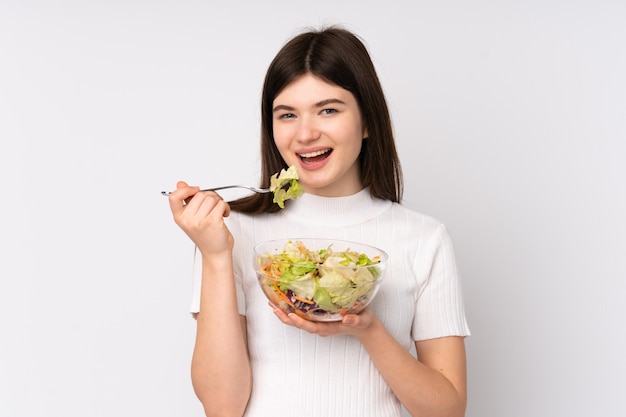 Joven adolescente sosteniendo una ensalada sobre pared blanca