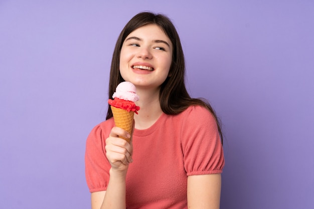 Joven adolescente sosteniendo un helado de cucurucho sobre pared púrpura