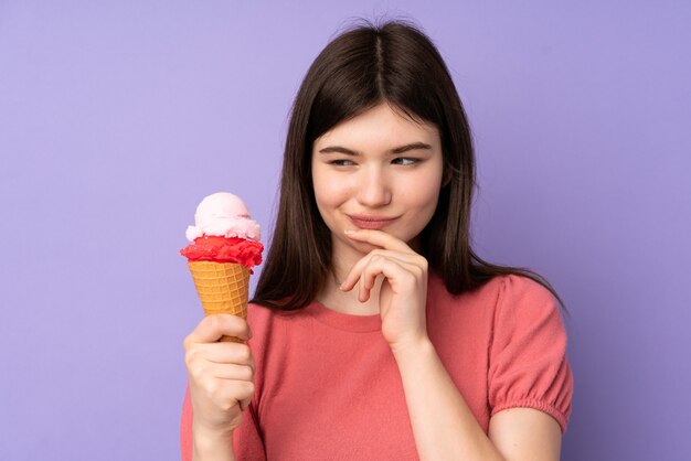 Joven adolescente sosteniendo un helado de cucurucho sobre pared púrpura