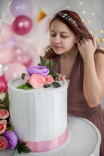 Foto joven adolescente en su cumpleaños con un gran pastel y globos