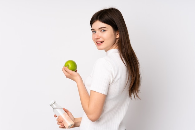 Joven adolescente ucraniana sobre pared blanca aislada con una manzana y con una botella de agua