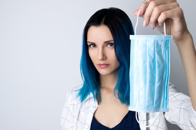 Joven adulta con cabello azul con máscara protectora