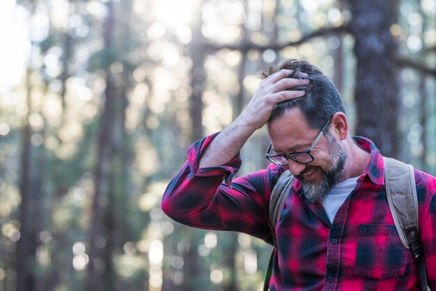 Joven adulto con barba y anteojos disfruta de actividades de ocio al aire libre en el bosque del parque forestal