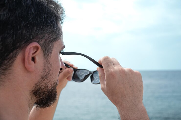 Joven adulto quitándose las gafas de sol contemplando el hermoso horizonte de la playa