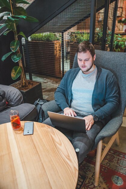 joven adulto trabajando en una computadora portátil en un café bebiendo té de frutas estilo de vida independiente