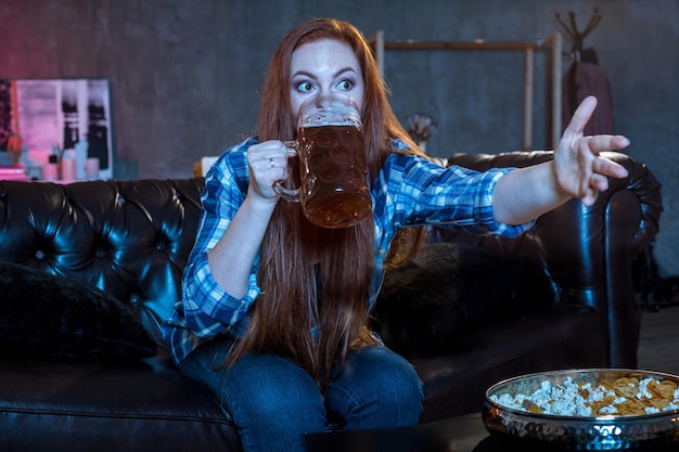 Joven aficionado al deporte viendo partido bebiendo cerveza