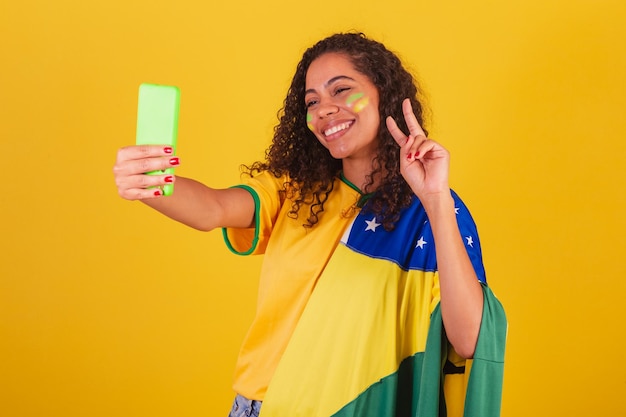 Foto joven aficionado al fútbol brasileño negro haciendo autorretrato en smartphone selfie