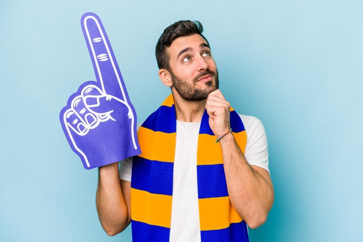 Foto joven aficionado a los deportes aislado de fondo azul mirando de lado con expresión dudosa y escéptica
