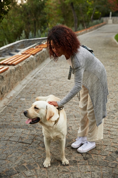 Joven africana acariciando a un perro en la calle