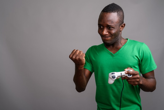 Joven africana con camisa verde en la pared gris