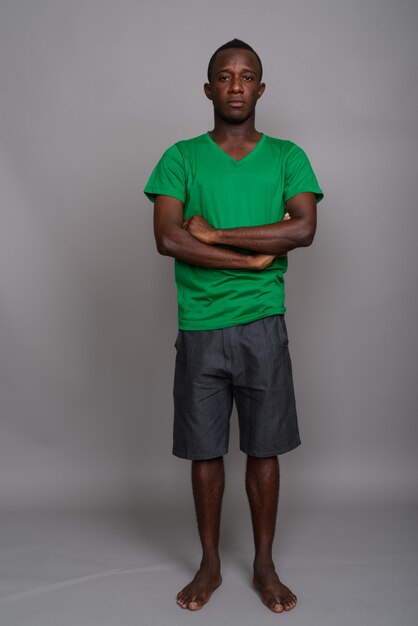 Foto joven africana con camisa verde en la pared gris